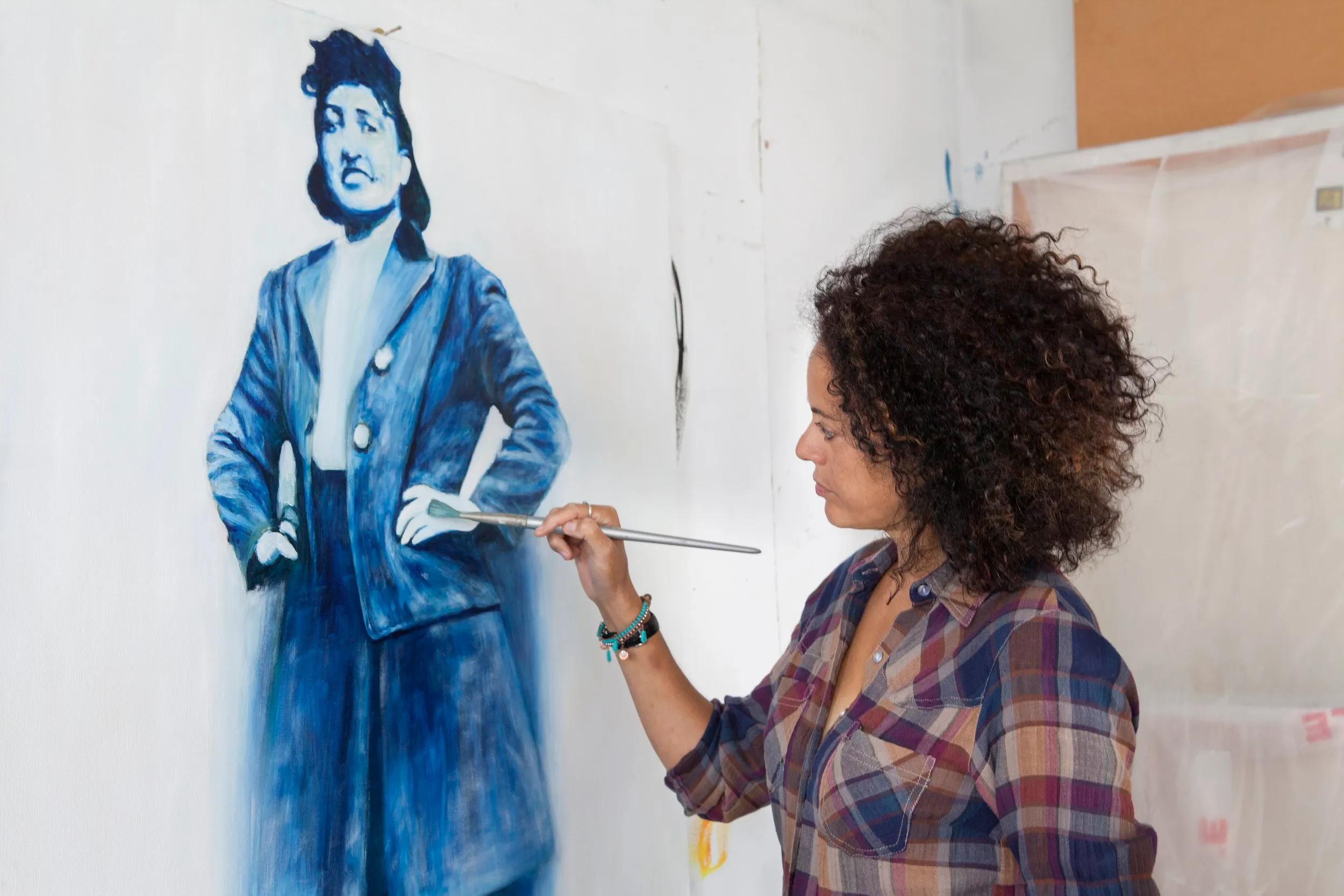 Helen Wilson Roe painting a blue-toned portrait of Henrietta Lacks in her studio