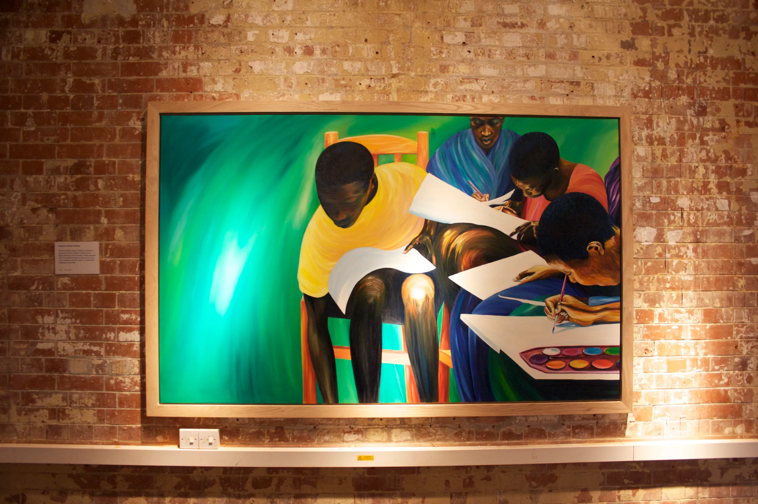 Large painting of Rwandan children sitting together painting with watercolours on paper propped on their knees