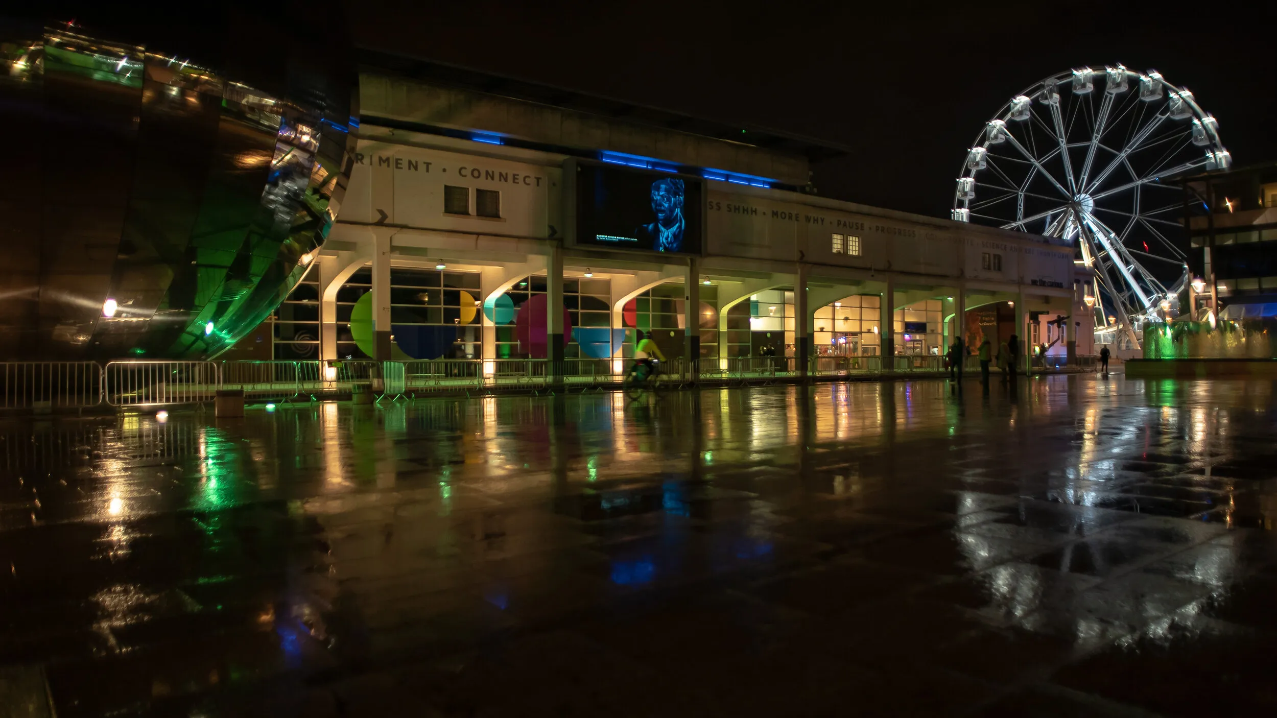 Night view of Millennium Square with another blue-toned portrait shown on the big screen